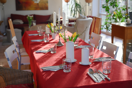 Improvised dining table for many guests with red tablecloth and decoration in the living roomの写真素材