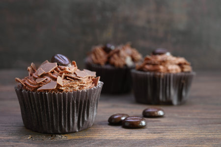 brown cupcakes with cocoa butter cream, chocolate chips and coffee beans on rustic wood, copy space, selected focus, narrow depth of fieldの写真素材