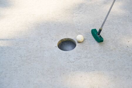 mini golf club hits the ball into the hole on a track from concrete, copy space, selected focusの写真素材