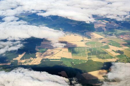 View through the clouds to a wind farm with many wind turbines in an agricultural landscapeの写真素材