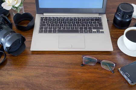 Wooden desktop from a photographer with laptop, camera, lenses and coffee, copy space, selected...