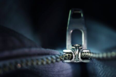 metal zipper macro shot, incisive technical invention for sewing and clothing industries, dark blue-grey background with copy space, selected focus, narrow depth of fieldの写真素材
