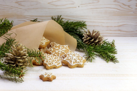 Gingerbread cookies for Christmas are falling out of a paper bag, fir branches and pine cones on a...