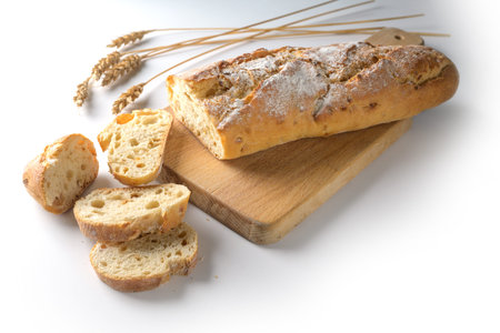 Baguette or French bread baked with onions on a wooden cutting board on a white background, copy...