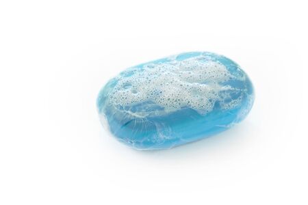 A bar of blue soap with lather and bubbles isolated on a whiteの写真素材