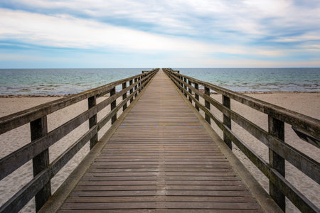 Wooden pier leads straight over the beach and the sea to the horizon, concept for the way forward...