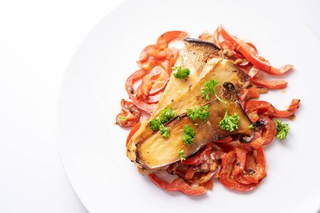 King oyster mushrooms on red bell pepper with parsley garnish served on a white plate, healthy vegetable meal for low carb diet and vegetarians, copy space, high angle view from aboveの写真素材