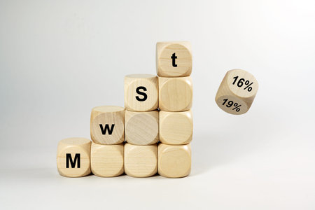 MwSt (value added tax) written on wooden dices, one is falling and turns from 19% to 16% on white