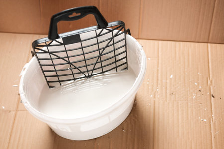 View into a plastic bucket with white wall paint and a drip grid for an apartment renovation, copy...