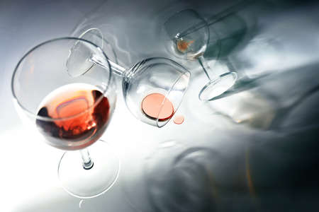 Glasses with red wine, standing, falling and rolling in unusual perspectives, abstract concept of a party with too much alcohol, copy space, selected focus, motion blurの写真素材