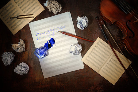 Violin, plain and crumpled sheet of music, handwritten beginning of a musical composition and a...
