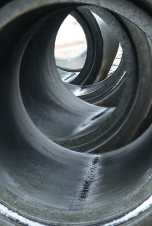 Tunnel view through a row of concrete rings for drainage pipe or well construction, abstract industry background, selected focus, narrow depth of fieldの写真素材