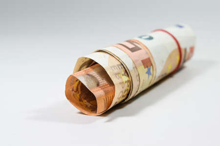 Some 50 euro notes rolled up into a small roll on a light background with copy space, selected focus, very narrow depth of fieldの写真素材