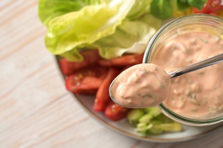 Thousand Island sauce based on skyr on a spoon and in a glass jar over slices of lettuce and tomato...