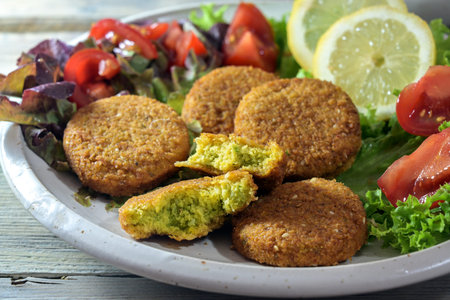 Vegetarian falafel from spiced chickpeas with salad of lettuce, tomatoes and lemon slices on a...