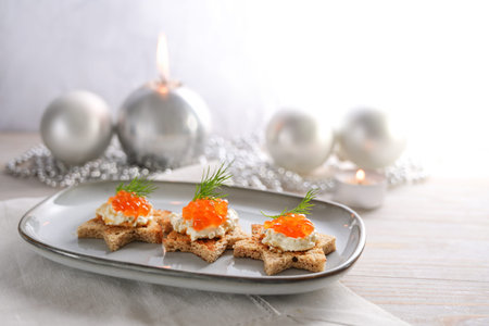 Festive red caviar canapes on toasted bread in star shape with cream and dill garnish on a gray plateの写真素材