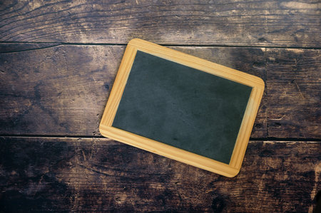Small blank chalkboard with copy space on dark rustic wooden planks, selected focus