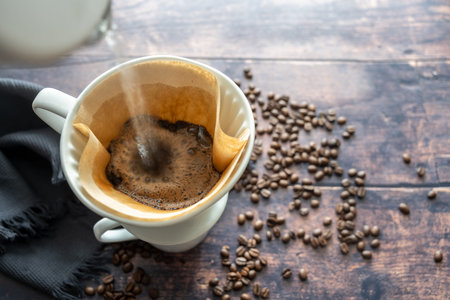 Pouring boiling water on ground coffee in a paper filter and a porcelain holder on a mug for an...
