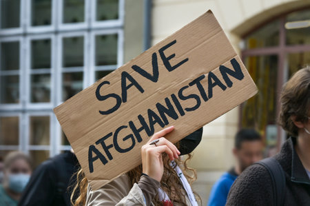Female activist holding a cardboard sign with text Safe Afghanistan at a demonstration in Lubeck,...
