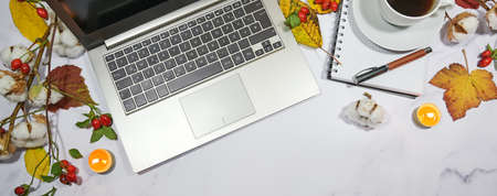 autumn desktop with laptop computer keyboard, notepad, colorful leaves and candles, seasonal home office in panoramic format with copy space, high angle view from aboveの写真素材
