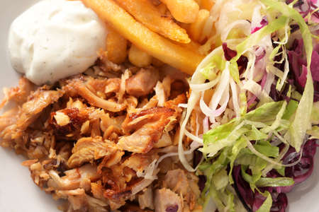 Roasted doner kebab chicken meat with french fries, salad and tzatziki dip, high angle view from above, full frame close-up shot, selected focus, narrow depth of fieldの写真素材