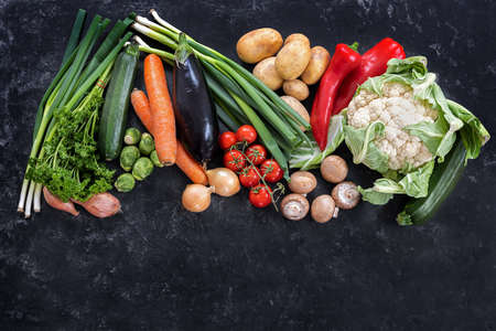 Fresh vegetables of different varieties on a dark slate background, diet food concept for fitness and lose weight, copy space, high angle view from above, selected focusの写真素材