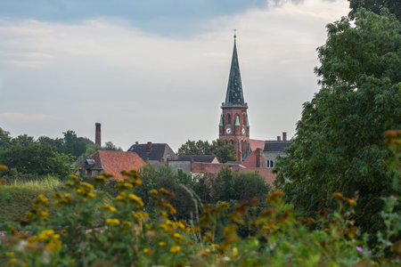 Church of the town Domitz against a cloudy sky in the green natural landscape on the river Elbe in...