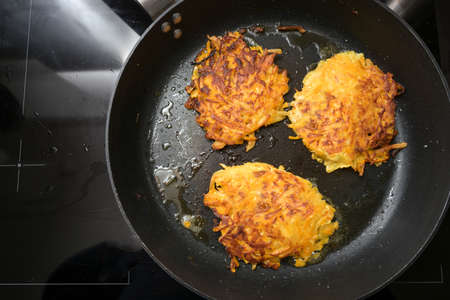 Golden roasted vegetable fritters from potato and red kuri squash in a black pan, also called pumpkin rosti or autumn pancake, copy space, high angle view from above, selected focusの写真素材