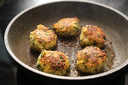 Fried vegetable balls of zucchini, potatoes and ginger in a pan on the stove, healthy cooking vegan...