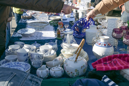 Garage sale or flea market stall with used tableware and customer hands on a sunny day, selected...