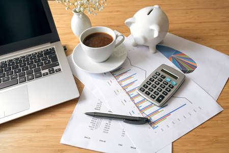 Office desk with finance accounting papers, laptop computer, calculator and piggy bank, business concept, selected focus, narrow depth of fieldの写真素材
