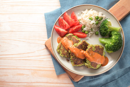 Vegetable patties with broccoli, tomato, rice and a hot sauce, vegetarian and vegan meal on a plate...