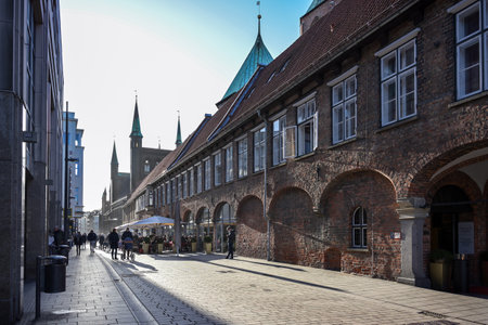 cLubeck, Germany, January 15, 2022: People in backlight on a shopping trip and in a street cafÃ© beside the historic town hall in the city center, tourist destination, selected focus, narrow depth of fieldのeditorial素材