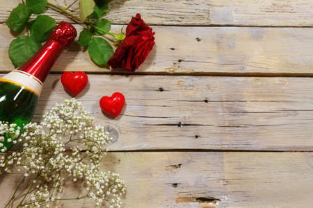 Romantic invitation with champagne, red rose and two hearts on a rustic wooden background, love concept for Valentine's Day, copy space, high angle view from aboveの写真素材