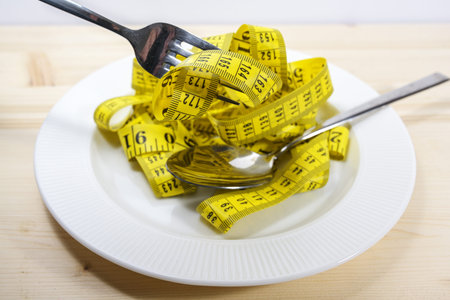 Tape measure like pasta on a plate with fork and spoon, diet concept to lose weight, selected focus,...