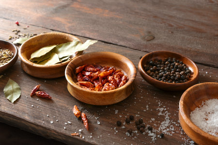 Spices in small bowls like bay leaves, salt, pepper and chili on a rustic wooden table, copy space, selected focus, narrow depth of fieldの写真素材