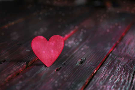 Pink heart on dark rustic wooden planks, flashy love concept for valentines, mother's day, father's day or birthday, copy space, selected focus, narrow depth of fieldの写真素材