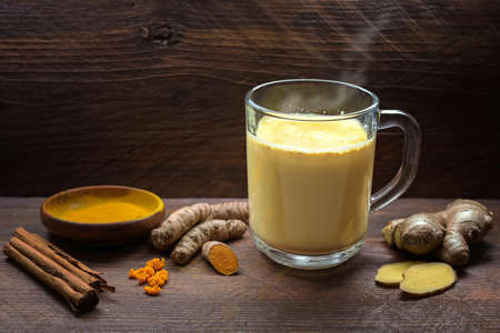 Golden milk with turmeric, ginger, cinnamon and more spices, healthy hot drink from Indian medicine Ayurveda to strengthen the immune system, dark rustic wood, copy space, selected focus, narrow depth of fieldの写真素材