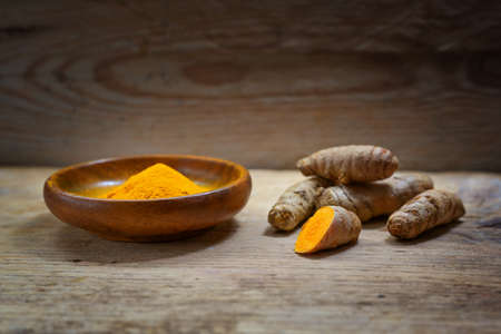 Turmeric, whole roots and powder against a rustic wooden background, healthy spice, anti-inflammatory and antioxidant, copy space, selected focus, narrow depth of fieldの写真素材