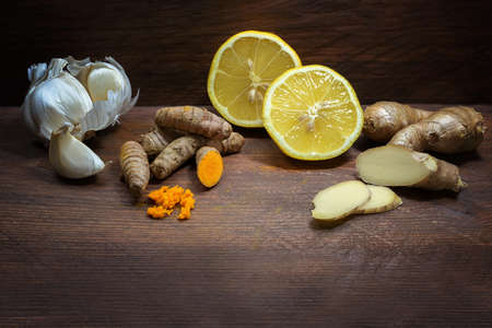 Garlic, turmeric, lemon and ginger, food ingredients for a healthy life, dark wooden table with copy space, selected focus, narrow depth of fieldの写真素材