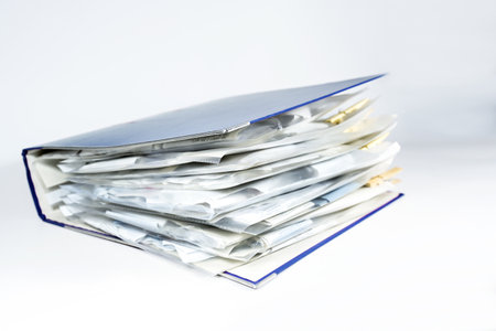 Large ring binder with clear punched pockets full of receipts, office management, accounting and tax calculation, light gray background, copy space, selected focus, narrow depth of fieldの写真素材