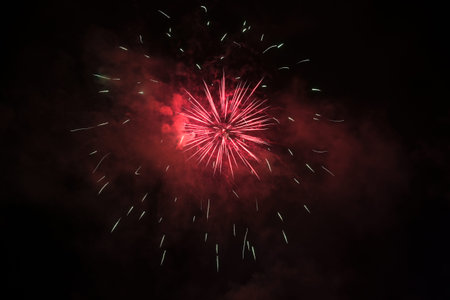 Red fireworks and smoke against the black night sky, festive highlight for holiday like new year,...