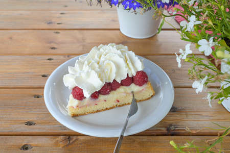 Cake with fresh raspberries and whipped cream on a rustic wooden table, fruit dessert in summer, copy space, selected focus, narrow depth of fieldの写真素材