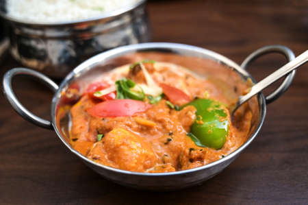 Indian chicken curry dish with vegetables in a steel bowl served with rice on a dark brown wooden table, copy space, selected focus, narrow depth of fieldの写真素材