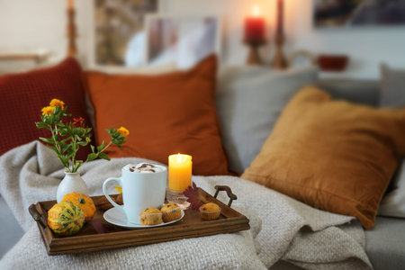 Relaxation with hot chocolate on a tray with candles and autumn decoration on the couch in a cozy...