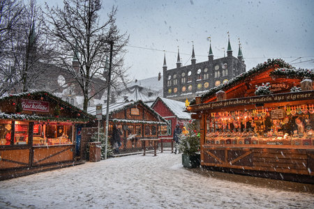 Lubeck, Germany, December 15, 2022: Christmas market in the snow with romantic stalls and the historic town hall of Lubeck in the background, copy space, selected focus, motion blurのeditorial素材