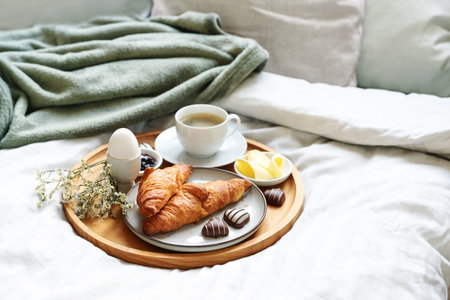 Mother's day breakfast served with love on bed. Coffee, croissant, egg and chocolate hearts on a...