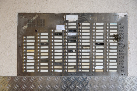 Many door bells without names on a dirty metal plate at the entrance of a large apartment building,...