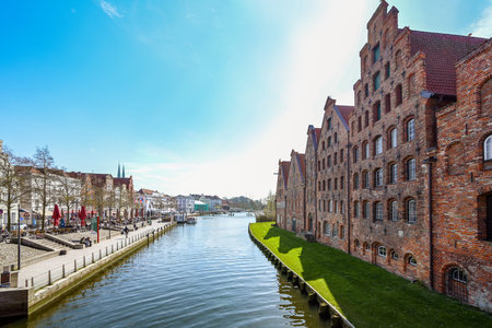 Lubeck, Germany, April 17, 2023: Historic salt store buildings and promenade with cafes on the banks...