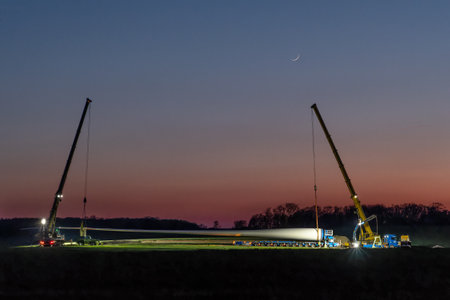 Rieps, Germany, April 21, 2023: Wind turbine blade, transport with special vehicle and alignment with two cranes at night, copy space, selected focusのeditorial素材